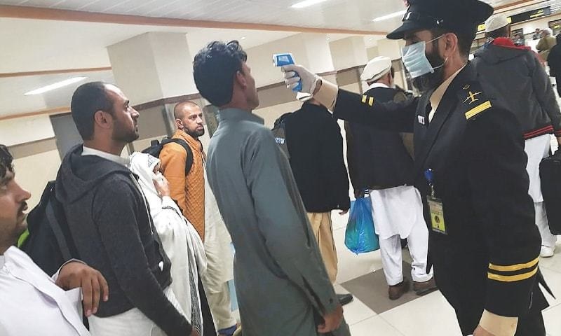 A Pakistani official checks passengers' temperature. — AP/File