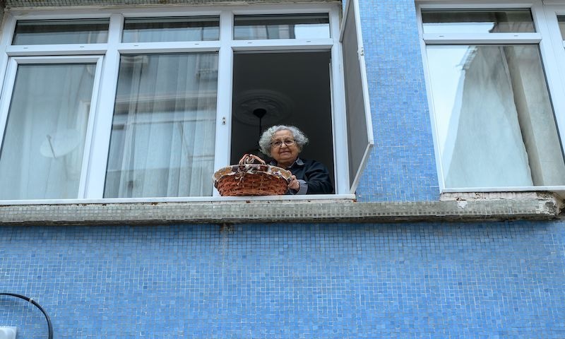 Lutfiye Yesilbas, 89-years-old Turkish woman who lives alone in her home lowers down her basket as her neighbour (not pictured) waits to take it at Kadikoy, in Istanbul, on March 23, 2020. This age-old practice, still a familiar sight on the streets of Istanbul, has gained new relevance since the authorities ordered people aged over 65 to stay at home to battle the Covid-19, the disease caused by the novel coronavirus. — AFP