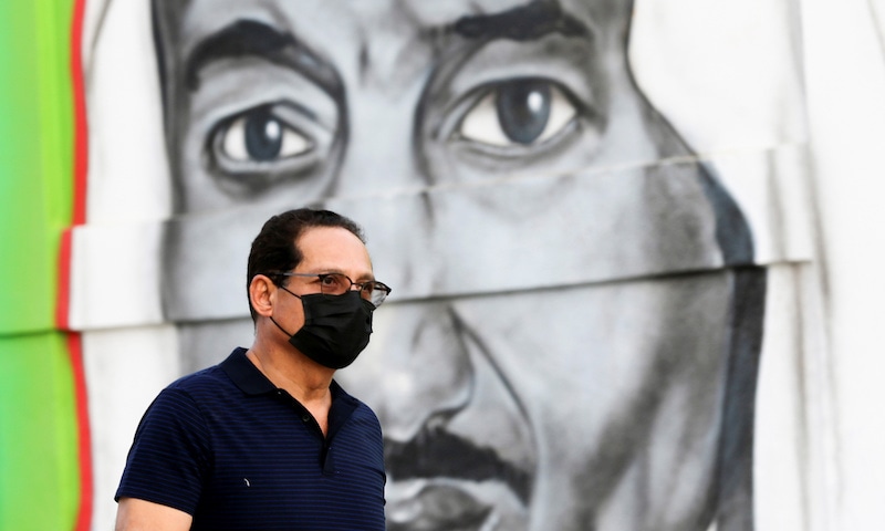 A Saudi man walks past a poster depicting Saudi King Salman bin Abdulaziz, after a curfew was imposed to prevent the spread of the coronavirus disease in Riyadh, Saudi Arabia on March 25, 2020. &mdash; Reuters