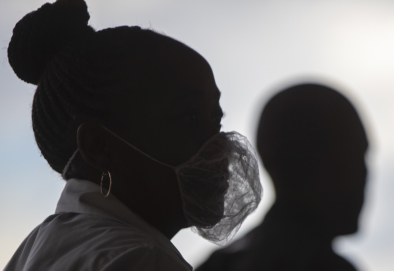A woman wearing a disposable white beard mask, to protect against coronavirus, stands outside the entrance of a shopping supermarket in Soweto, South Africa on Thursday, March 26, 2020. In just hours, South Africa goes into a nationwide lockdown for 21 days, in an effort to mitigate the spread to the coronavirus. — AP