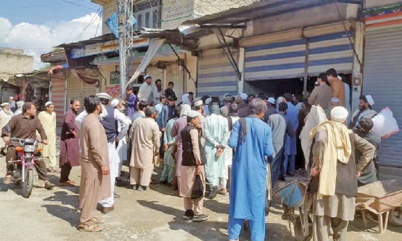 Locals gather outside a shop in Khar, Bajaur, to get subsidised flour. — Dawn