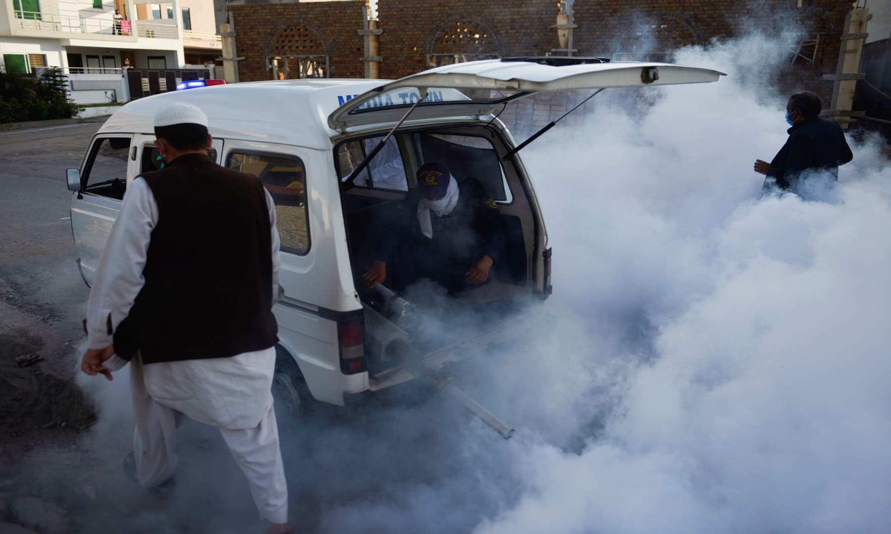 Workers fumigate in a residential area in Rawalpindi. — AFP