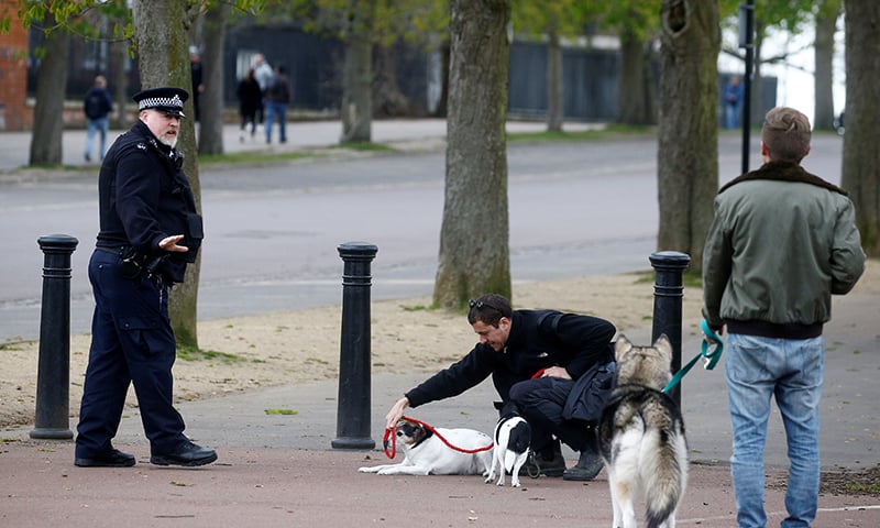 A police officer with people and dogs at Greenwich Park as the spread of the coronavirus disease continues, London, Britain, March 31. — Reuters