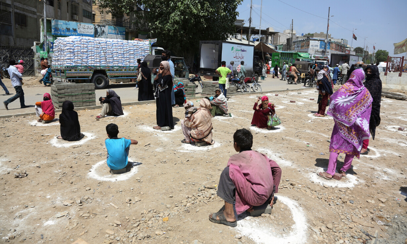 People sit at a distance to receive relief goods during a nation-wide lockdown to contain the Covid-19 outbreak, in Karachi, Pakistan on March 27. —AP