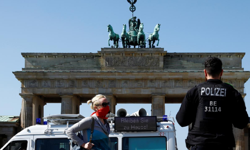 A police officer speaks with a woman next to a police car with a sign attached reading "Stay at home!" in front of Brandenburg Gate, during Covid-19 outbreak in Berlin, Germany April 5. — Reuters
