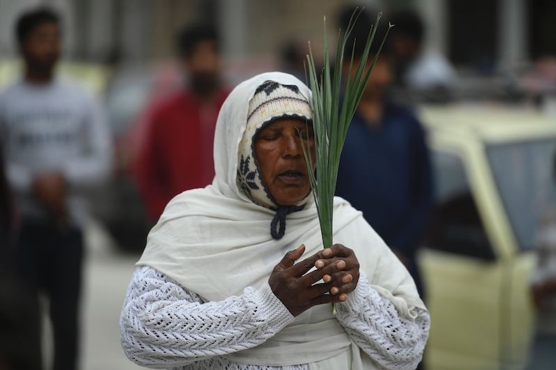A Christian devotee stands in circles marked on the ground to maintain social distancing holds palm branch to celebrate a Palm Sunday service at the Christian neighborhood during a government-imposed nationwide lockdown as a preventive measure against the COVID-19 coronavirus, in Islamabad on April 5, 2020. (Photo by Aamir QURESHI / AFP) &mdash; AFP or licensors