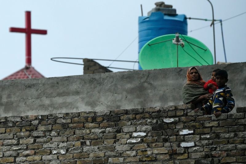 A Christian woman and her children watch from her house roof a Palm Sunday service at the Christian neighborhood during a government-imposed nationwide lockdown as a preventive measure against the COVID-19 coronavirus, in Islamabad on April 5, 2020. (Photo by Aamir QURESHI / AFP) &mdash; AFP or licensors