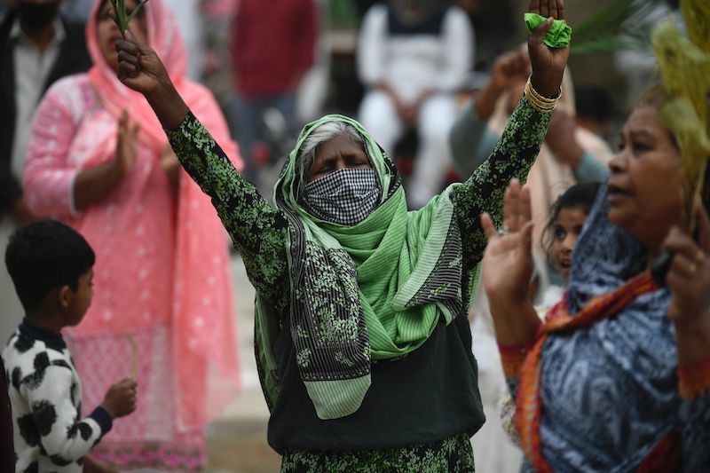 Christian devotees stand in circles marked on the ground to maintain social distancing as they hold palm branches to celebrate a Palm Sunday service at the Christian neighborhood during a government-imposed nationwide lockdown as a preventive measure against the COVID-19 coronavirus, in Islamabad on April 5, 2020. (Photo by Aamir QURESHI / AFP) &mdash; AFP or licensors