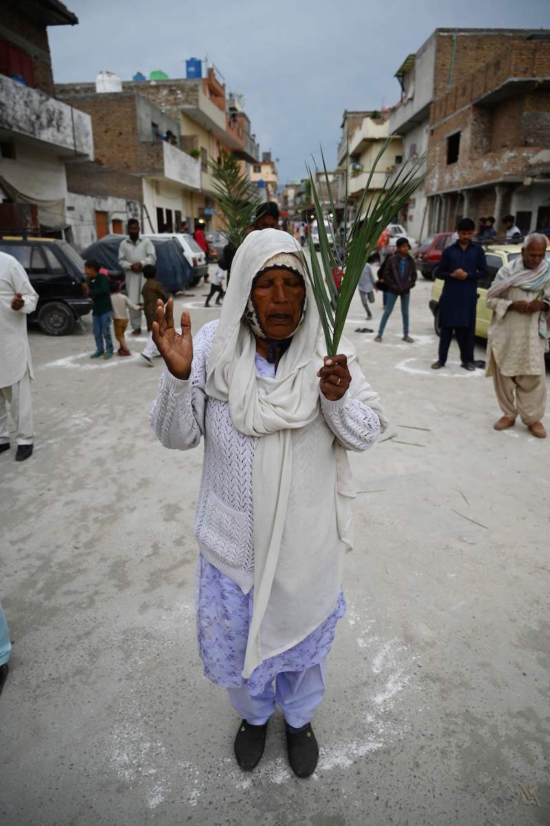 Christian devotees stand in circles marked on the ground to maintain social distancing as they hold palm branches to celebrate a Palm Sunday service at the Christian neighborhood during a government-imposed nationwide lockdown as a preventive measure against the COVID-19 coronavirus, in Islamabad on April 5, 2020. (Photo by Aamir QURESHI / AFP) &mdash; AFP or licensors