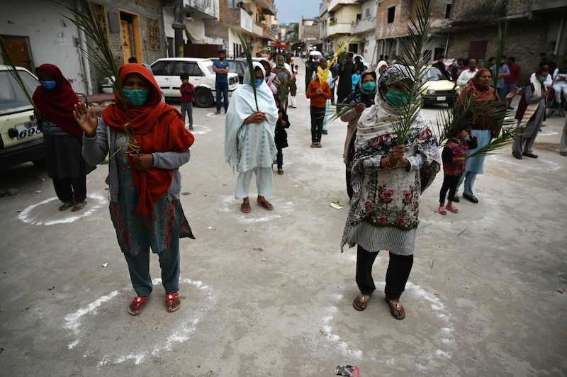 TOPSHOT - Christian devotees stand in circles marked on the ground to maintain social distancing as they hold palm branches to celebrate a Palm Sunday event at the Christian neighborhood during a government-imposed nationwide lockdown as a preventive measure against the COVID-19 coronavirus, in Islamabad on April 5, 2020. (Photo by Aamir QURESHI / AFP) &mdash; AFP or licensors