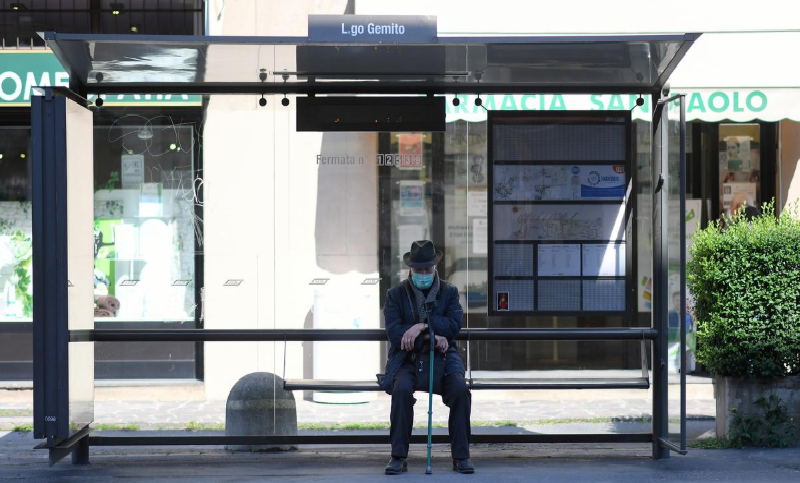 A man wearing a face mask sits at a bus stop, as the spread of Covid-19 continues in Milan, Italy, April 6. — Reuters