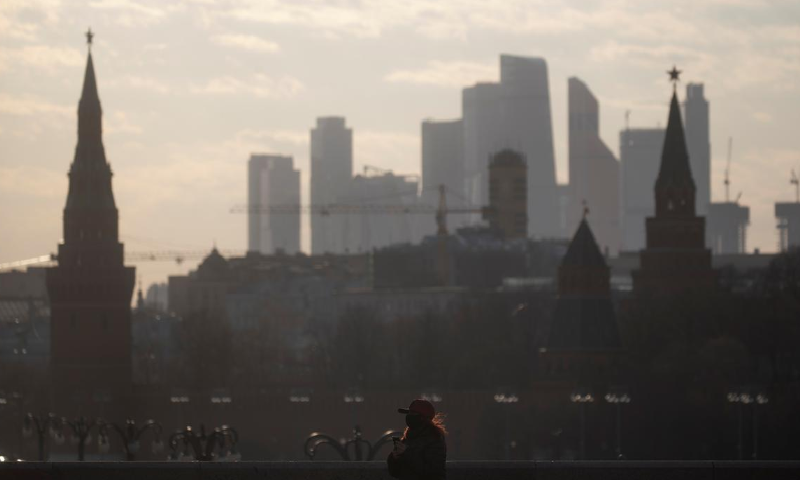 A woman in protective mask walks along the bridge, with the towers of Kremlin and skyscrapers of Moscow-City business centre in the background, as the spread of Covid-19 continues, in Moscow, Russia April 7. &mdash; Reuters