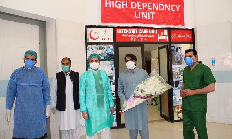 Junaid Khan, the first patient to have recovered from Covid-19 in Swat, receives a bouquet from medical staff after being discharged from hospital. — Photo by author