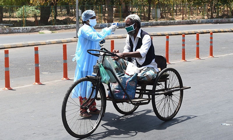 A health worker checks the body temperature of a man with mobility impairment in Ahmedabad on April 8. — AFP