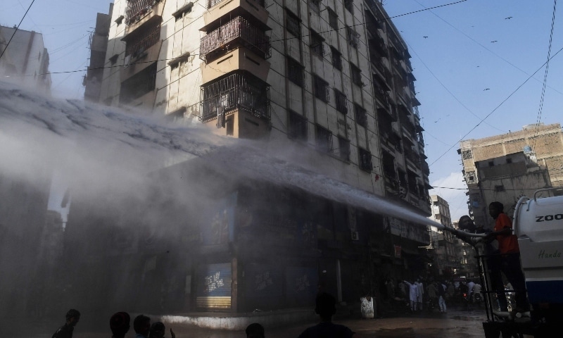 Workers sprays disinfectant at a residential area in Karachi on April 8. — AFP Workers sprays disinfectant at a residential area in Karachi on April 8. — AFP