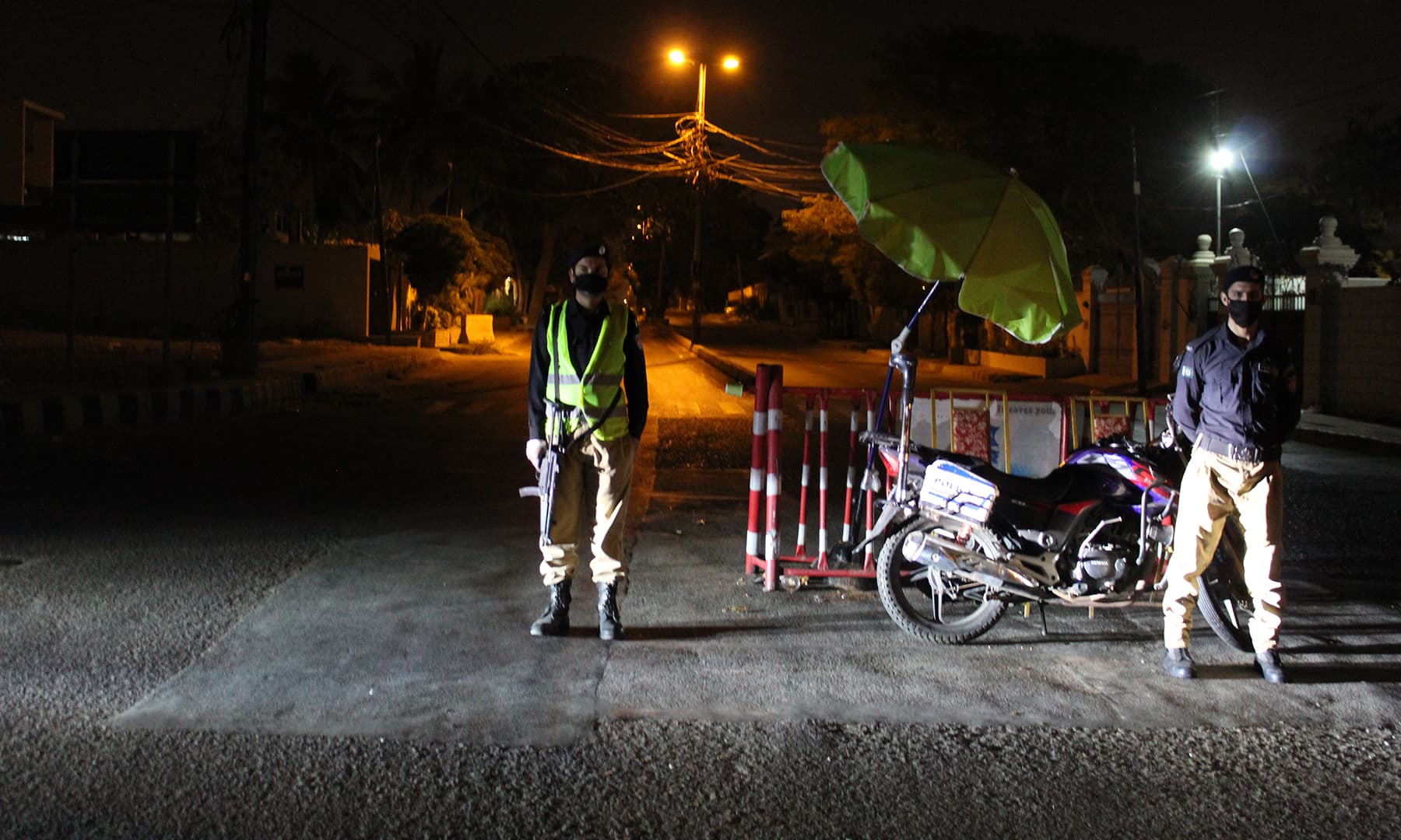 Policemen wearing masks stand guard at an empty street in Karachi.