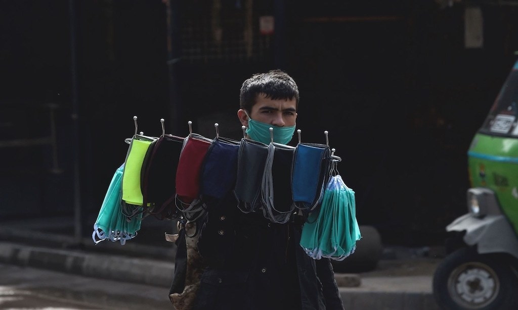 A vendor carries facemasks for sale | AFP