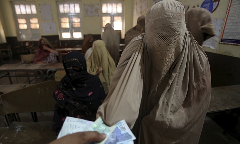 A woman receives cash under the Ehsaas Emergency Cash Programme for families in need in Peshawar. &mdash; AP
