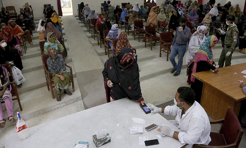 A woman scans her thumb for identification to receive cash in Karachi. &mdash; AP
