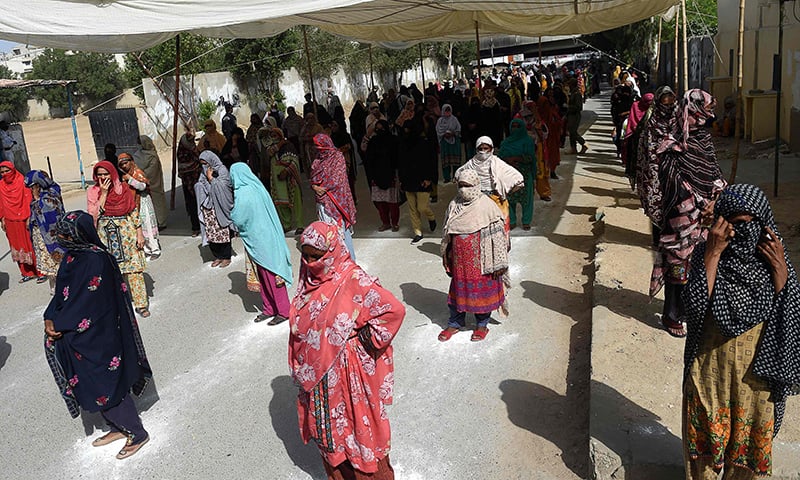 Women queue to collect cash through a mobile wallet under the governmental Ehsaas Emergency Cash Programme for people in need in Karachi on Saturday. &mdash; AFP
