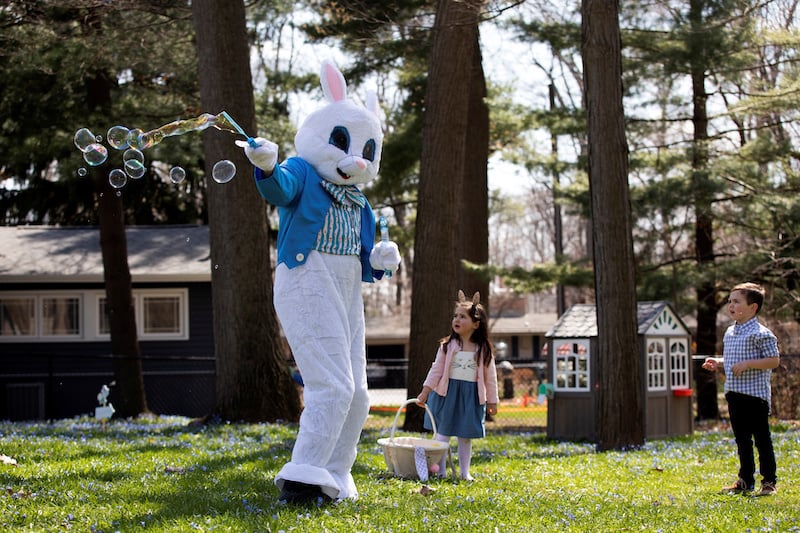 A person dressed as an Easter bunny blows bubbles with Genevieve Pina, 3, while making a surprise visit during a day full of Easter festivities, amid the ongoing coronavirus disease outbreak, in Plymouth, Michigan, US, on April 11, 2020. &mdash; Reuters