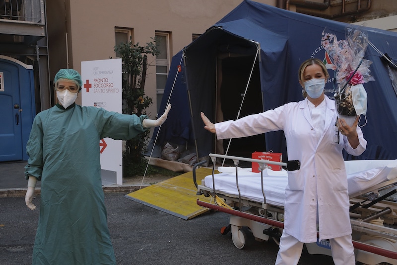 Monica Carfora, right, deputy head of the emergency of the Santo Spirito Hospital, which now has a separate emergency for possible Covid-19 patients, holds a chocolate Easter egg as she poses for a photograph with nurse Silvia Sforza, holding out their arms to indicating social distancing, outside the entrance for Covid-19 emergency, in central Rome on Sunday, April, 12, 2020. — AP