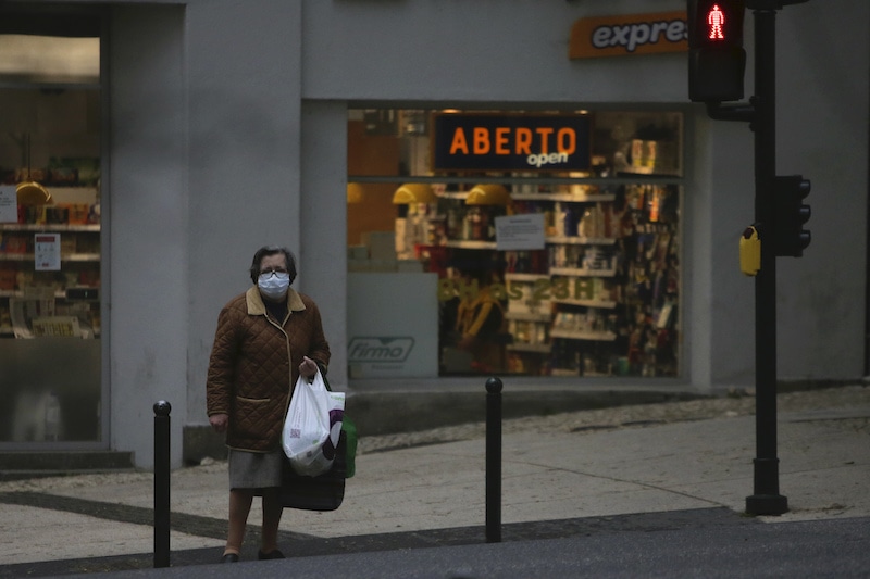 A woman carrying her shopping and wearing a face mask as protection against the new coronavirus leaves a supermarket in Lisbon, Portugal on Tuesday, April 14, 2020. — AP