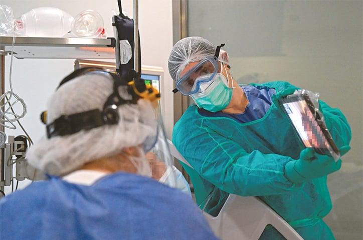 MADRID: A healthcare worker holds a tablet so that a Covid-19 patient could talk to relatives via video link in an intensive care unit of a hospital on Tuesday.—AFP