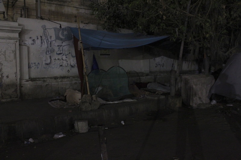 A man sleeps under a mosquito net on the footpath opposite the SIUT. — Photo by author