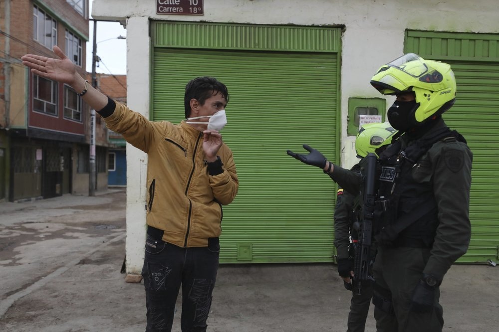 A policeman asks a resident for proof of identification during a curfew ordered by the city mayor in an effort to prevent the spread of the new coronavirus, in Soacha, Colombia, April 17. — AP