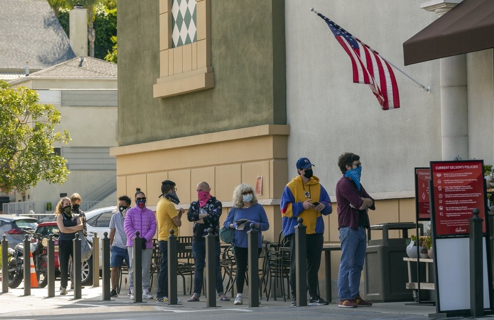 Customers wearing face masks line up outside Gelson's Market while saying apart during the coronavirus pandemic, in the Los Feliz area of Los Angeles on April 17. — AP