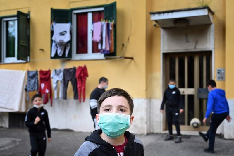 Children wearing protective face masks play football in front of their building in Rome's neighbourhood of San Basilio on April 18, 2020, during the country's lockdown aimed at stopping the spread of the novel coronavirus. — AFP