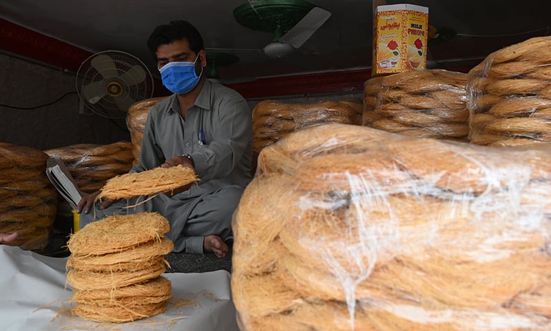A vendor wearing a facemask packs vermicelli for customers at a shop in Rawalpindi. &mdash; AFP