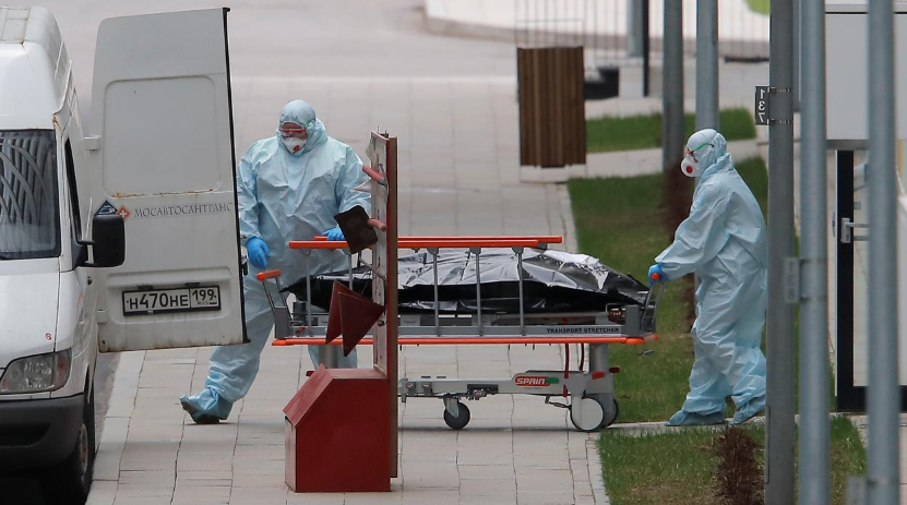 Medical specialists wearing protective gear push a stretcher towards an ambulance while relocating a non-transparent bag outside a hospital for patients infected with Covid-19 on the outskirts of Moscow, Russia, April 20. — Reuters