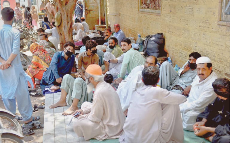 ATTENDANTS of hospitalised patients pack a footpath along the Dr Ruth Pfau Civil Hospital Karachi on Tuesday.—Fahim Siddiqi/White Star