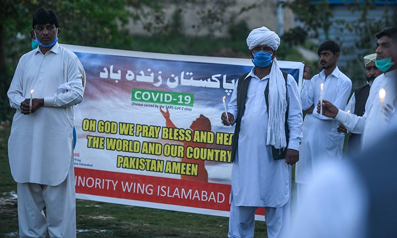 Activists of the minority wing of the PTI hold candles as they pray. &mdash; AFP