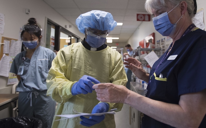 In this Tuesday, April 21, 2020 photo, Father Victor Fernandes puts on personal protection equipment prior to visiting a patient in the Covid-19 intensive care unit at St Paul's hospital in downtown Vancouver, British Columbia. — AP