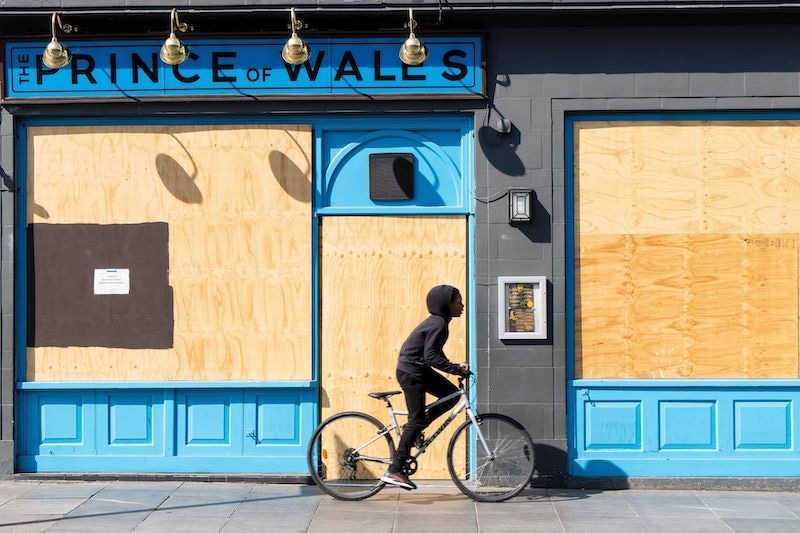 A boy cycles past the boarded up and shut Prince of Wales pub in Brixton, south London on April 23, 2020 as life in Britain continues under a lockdown designed to halt the spread of the novel coronavirus COVID-19 illness. — AFP