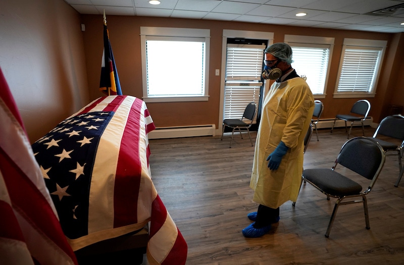 Michael Neel, funeral director of of All Veterans Funeral and Cremation, wearing full PPE, looks at the US flag on the casket of George Trefren, a 90-year-old Korean War veteran who died of the coronavirus disease in a nursing home, in Denver, Colorado, US on April 23, 2020. — Reuters