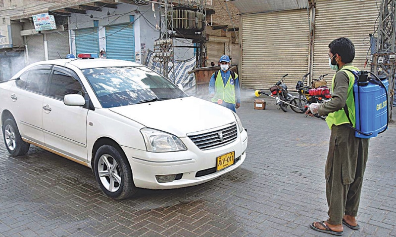 A VOLUNTEER disinfects a car in Larkana. — APP