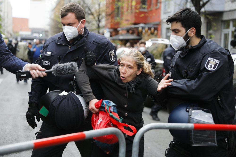 A woman talks to a reporter as she is detained by police officers during an illegal demonstration against the restrictions and measures to prevent the spread of coronavirus in Berlin, Germany. — AP