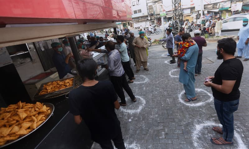 People maintaining a level of social distancing wait their turn to get traditional food from a bakery to break their fast on the first day of Ramazan, in Lahore on Saturday, April 25. — AP People maintaining a level of social distancing wait their turn to get traditional food from a bakery to break their fast on the first day of Ramazan, in Lahore on Saturday, April 25. — AP