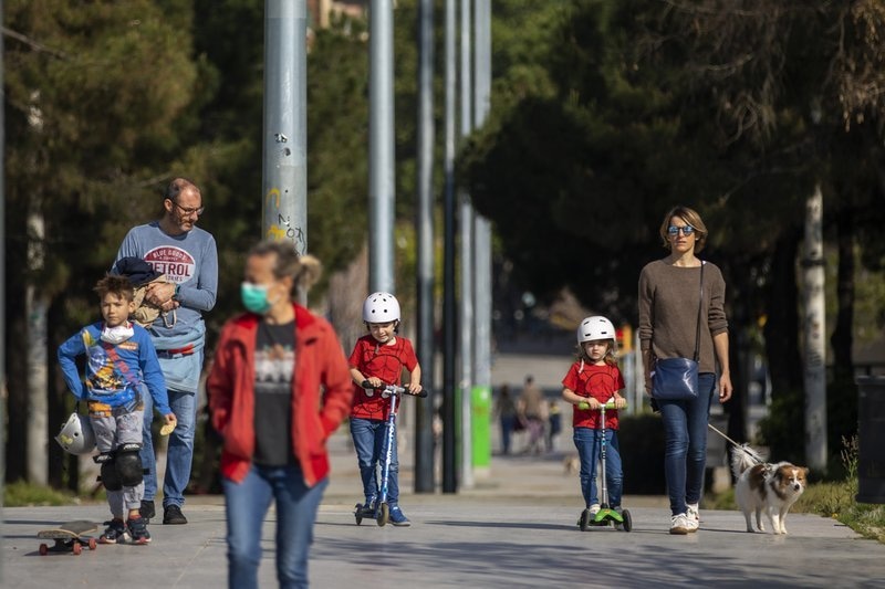 Families walk in the sunshine along a boulevard in Barcelona, Spain, April 26. — AP