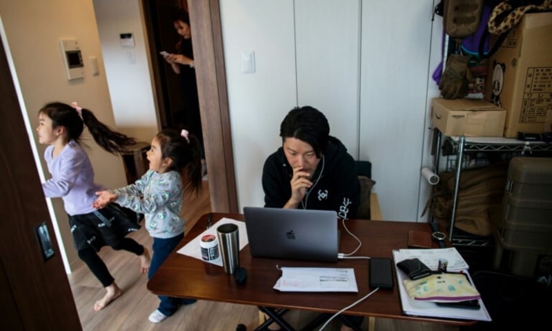 While her daughters play in the room next door, Yuki Sato, a Japanese employee of a start-up company, works at home. — AFP/File