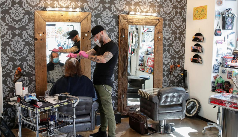 A client and barber Giuseppe Decarlo wear protective face masks at the Haarrock barber shop and tattoo studio on the opening day after the Swiss government eased the lockdown during Covid-19 outbreak in Zurich, Switzerland, April 27. — Reuters