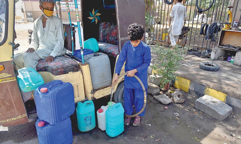 A young boy fills plastic cans with water to be carried home in the rickshaw.—White Star A young boy fills plastic cans with water to be carried home in the rickshaw.—White Star