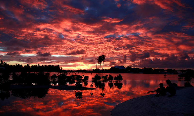Villagers watch the sunset over a small lagoon near the village of Tangintebu on South Tarawa in the central Pacific island nation of Kiribati, May 25, 2013. &mdash; Reuters