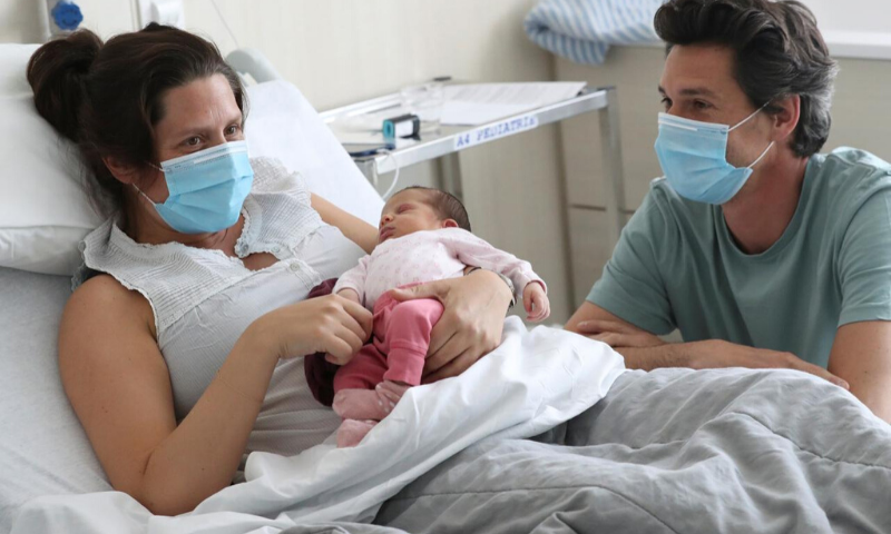 Amandine, who tested positive for the coronavirus just before giving birth, and Francois, wearing protective face masks, are pictured with their newborn daughter Mahaut. &mdash; Reuters