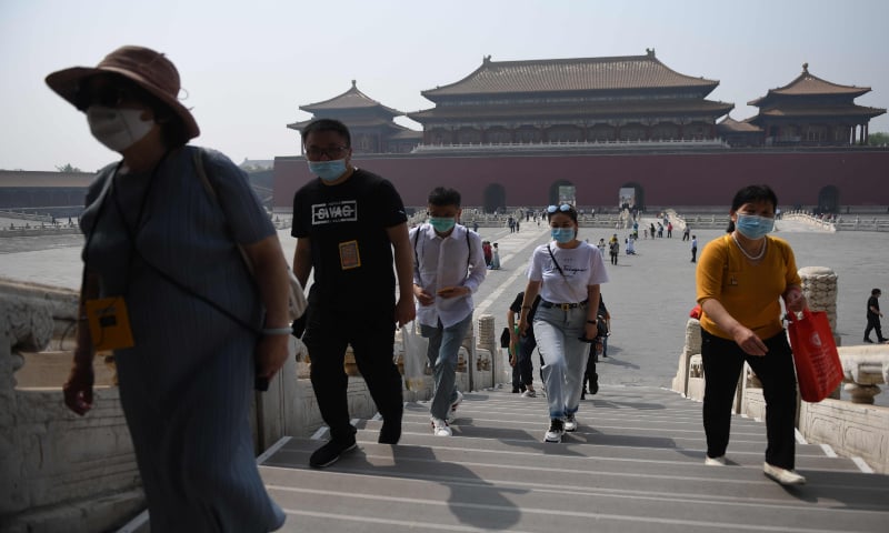 People wear face masks as a preventive measure against the COVID-19 coronavirus as they walk through the Forbidden City, the former palace of China's emperors, in Beijing. — AFP