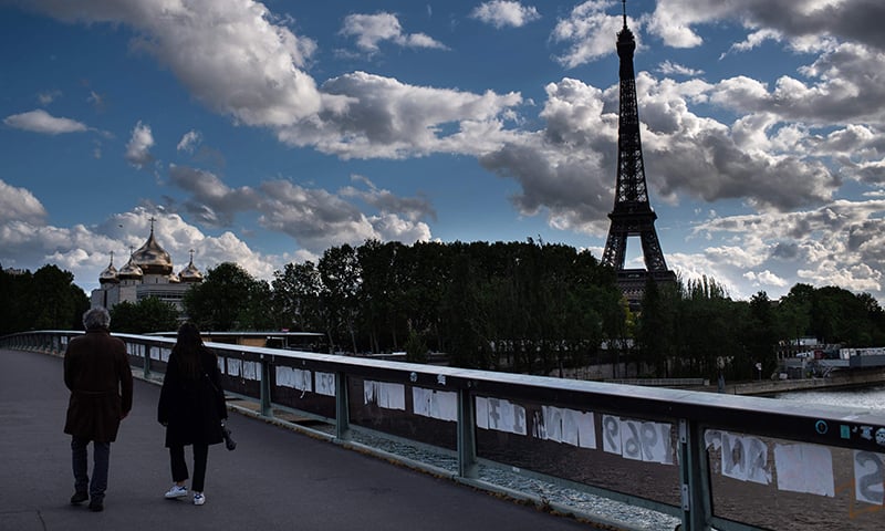 A man and a woman cross the Alma bridge over the river Seine on a cloudy day in Paris on May 1 on the 46th day of the lockdown. — AFP